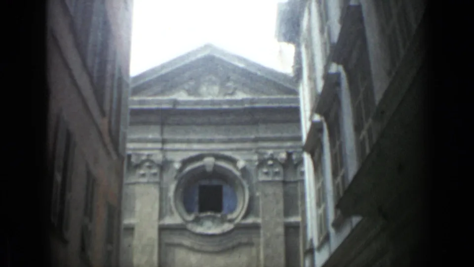 1962 Cannes frame centered higher on the facade, with the triangular pediment, oculus window, and shadowed alley walls visible.
