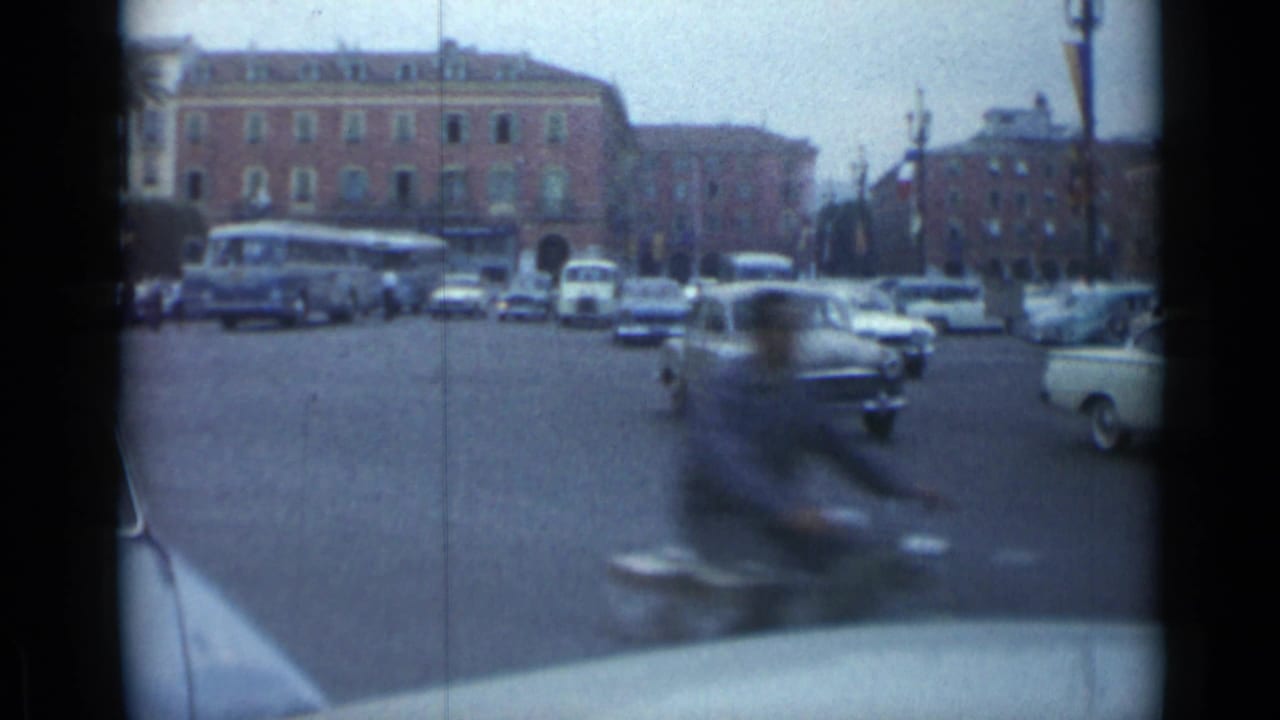 Motorcycle blurs past the camera as cars and buses move through an intersection.