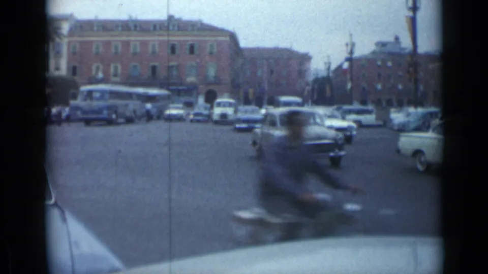 Cannes, France 1962 traffic scene with a blurred motorcycle in the foreground and period cars beyond.
