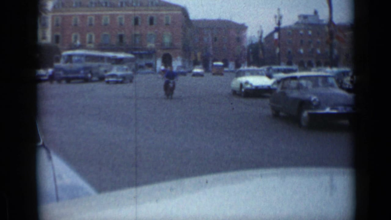 Wide Cannes intersection with cars, a bus, buildings, and a rider approaching through traffic.