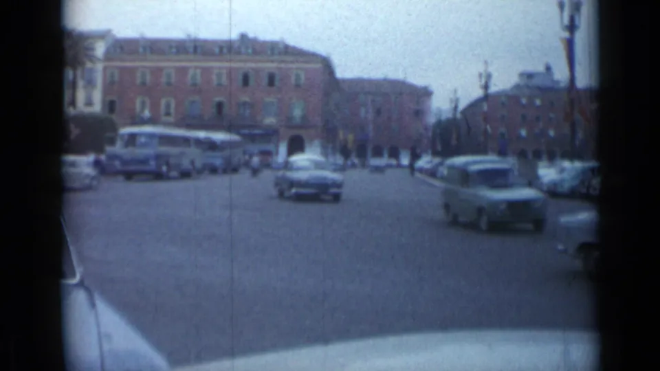 1962 Cannes avenue view from a moving vehicle, showing a bus, several cars, pedestrians, and urban buildings.