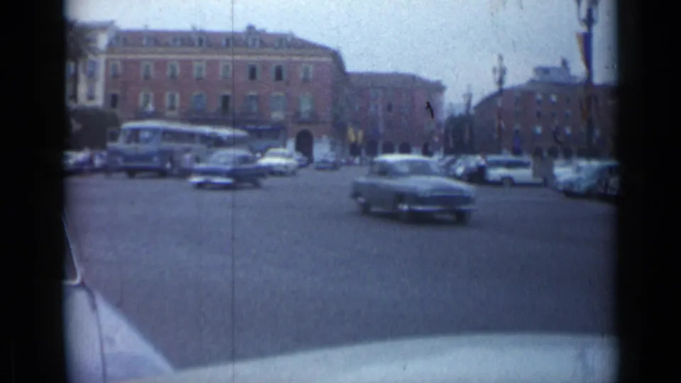 Cannes street traffic in 1962, with a dark sedan crossing the foreground and a bus and parked cars behind it.