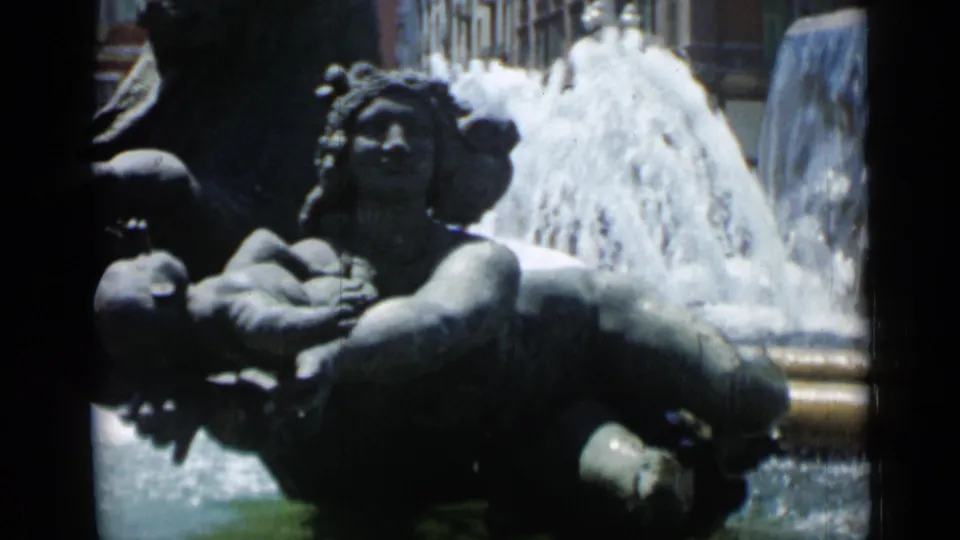 Cannes 1962 8mm frame showing a stone fountain group with human figures, a child-like form, and bright water spray.