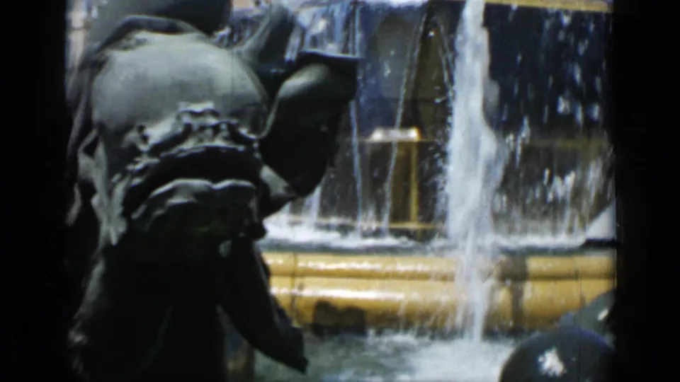 1962 Cannes frame focused on the bronze fountain sculpture, falling water, and yellow-toned basin rim in bright daylight.