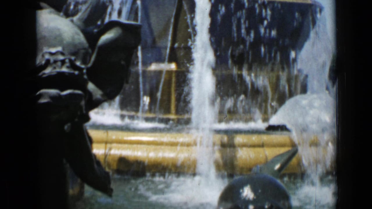 Close view of a tiered fountain with falling water and dark sculptural figures.