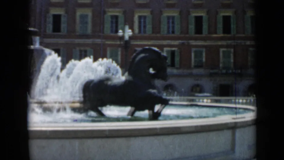 1962 Cannes frame showing the fountain rim, a dark horse sculpture, splashing water, and red facades with green shutters.