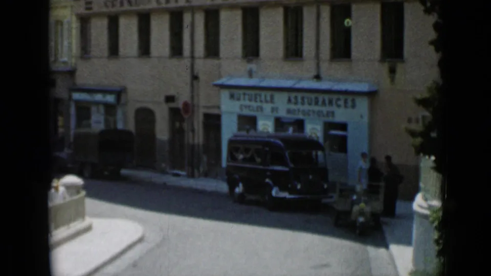 Cannes storefront marked MUTUELLE ASSURANCES CYCLES ET MOTOCYCLES, with a dark van outside and pedestrians near the curb.