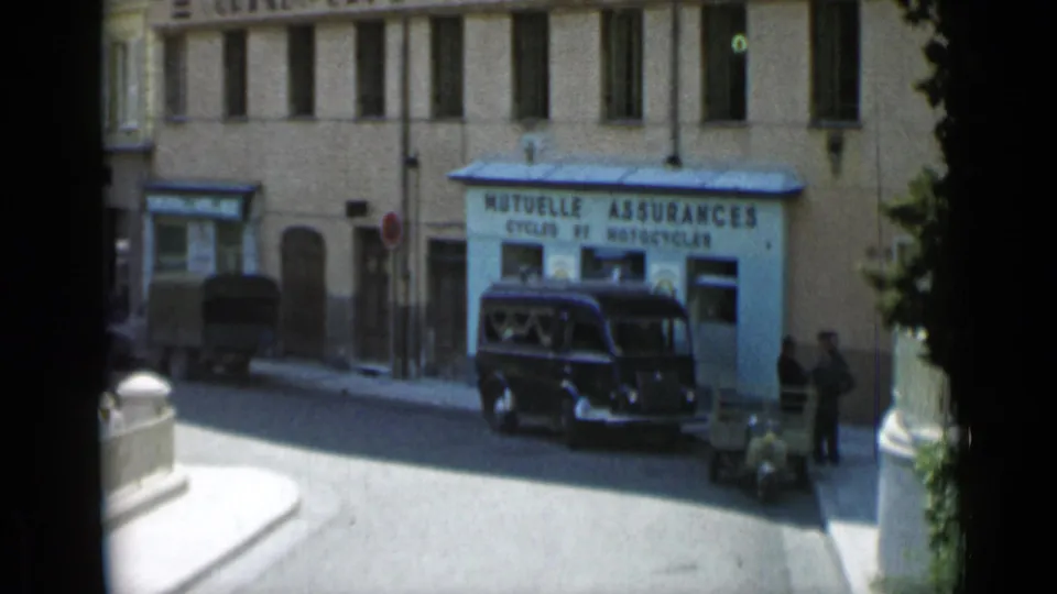 1962 Cannes street view centered on a dark van parked before a MUTUELLE ASSURANCES storefront, with people standing near the sidewalk.