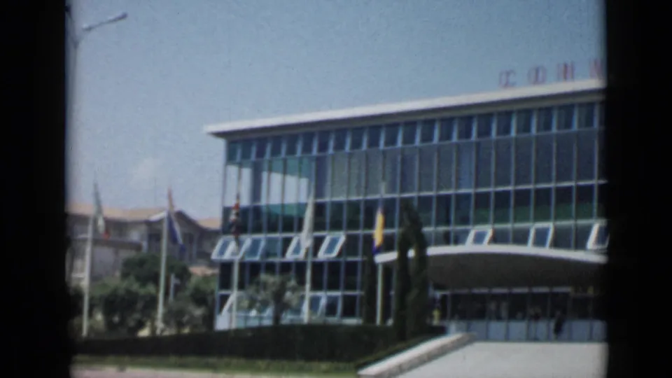 1962 Cannes view of a modern glass-fronted convention building with flags, entrance canopy, and partial rooftop lettering.