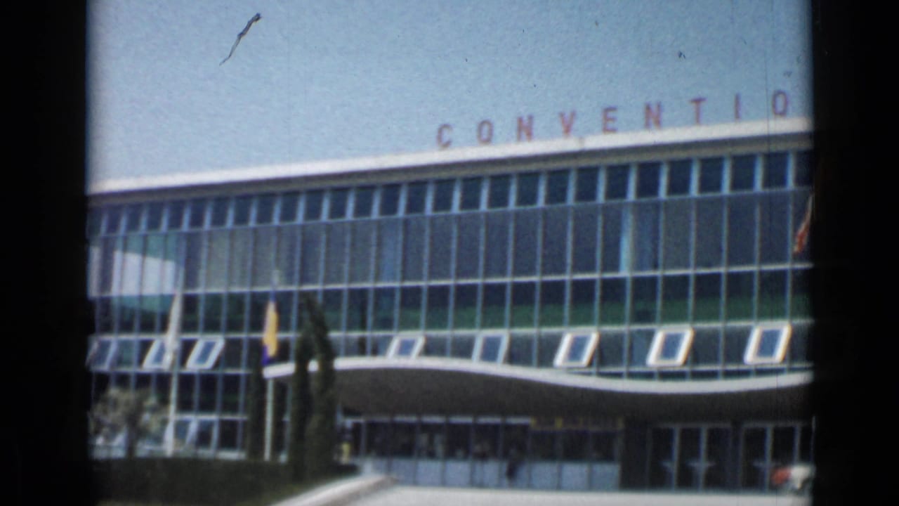 Cannes convention building facade in 1962, showing CONVENTION lettering, flagpoles, glass windows, and the shaded entrance.