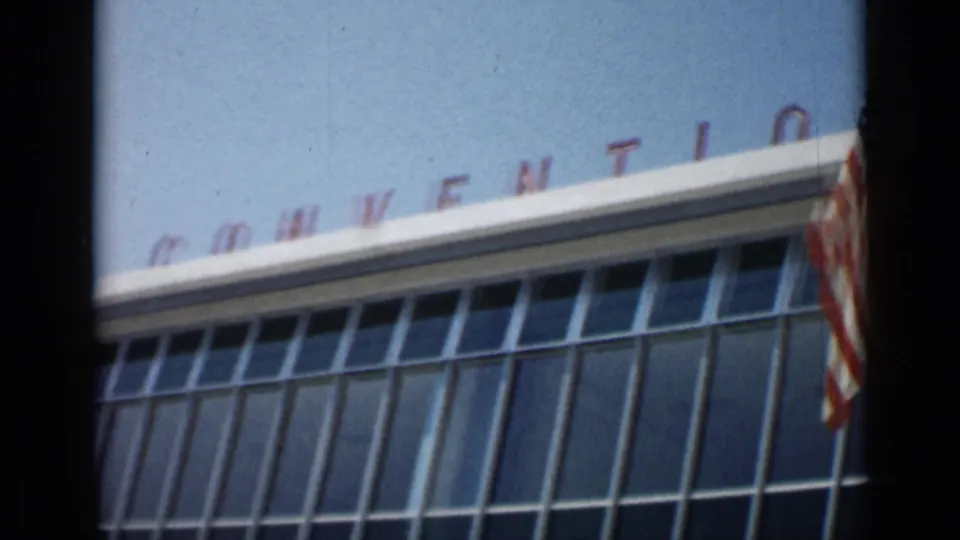 Cannes convention-center exterior in 1962 with angled window bays, roof lettering, and an American flag at the edge.