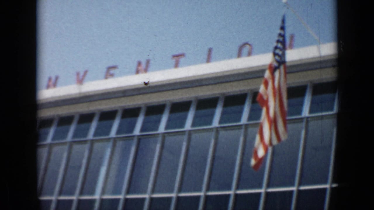 American flag in front of a glass building with partial CONVENTION lettering.