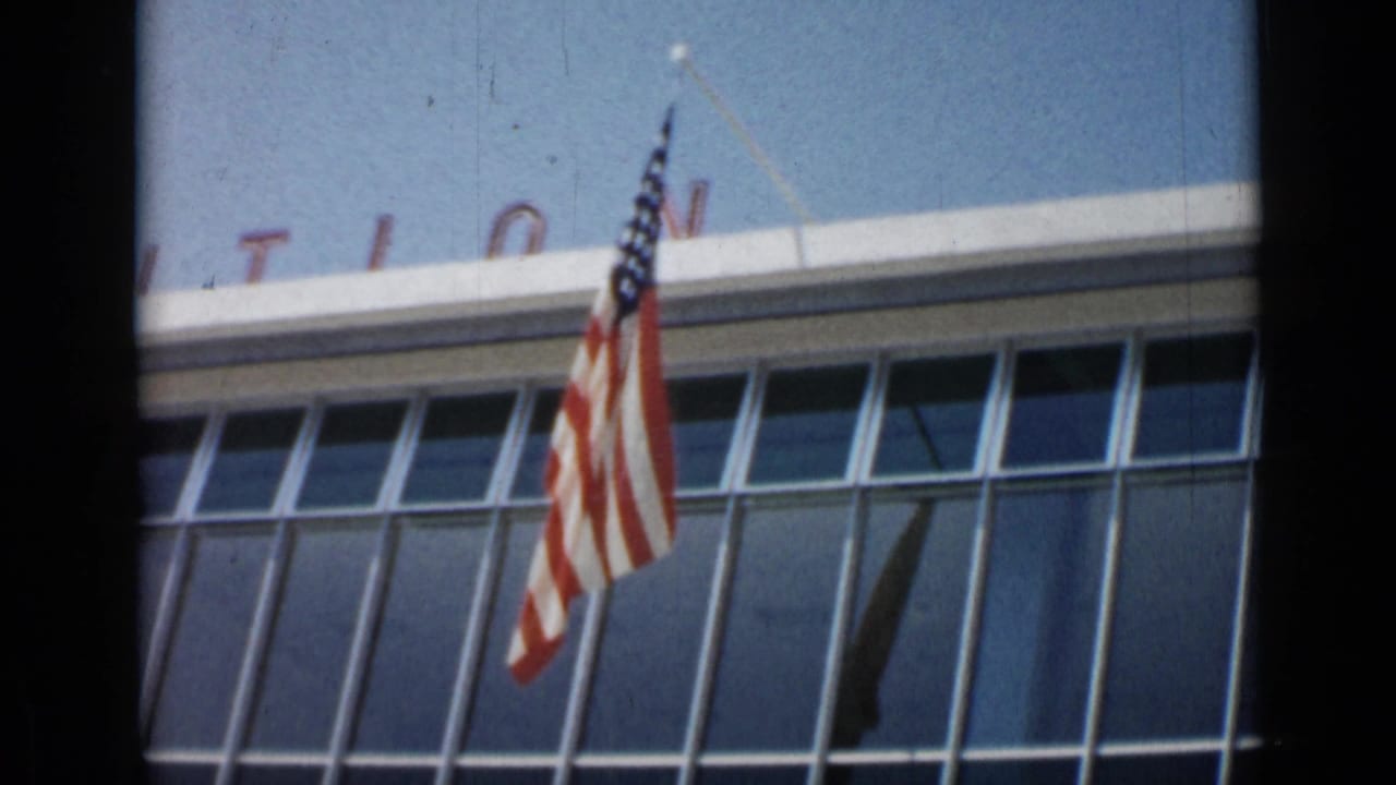 American flag centered against a glass-windowed building facade.