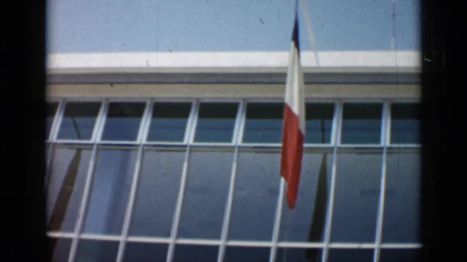 French flag shown before the glass-windowed convention building in the supplied Cannes 1962 footage.