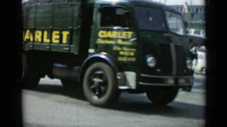 Green Charlett delivery truck with yellow lettering passing on a Cannes street in 1962 color 8mm footage.
