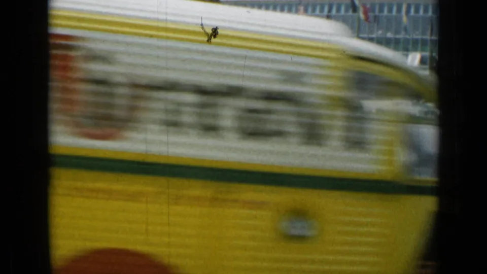 A blurred yellow vehicle crosses the foreground of a 1962 Cannes street scene with a modern building behind it.