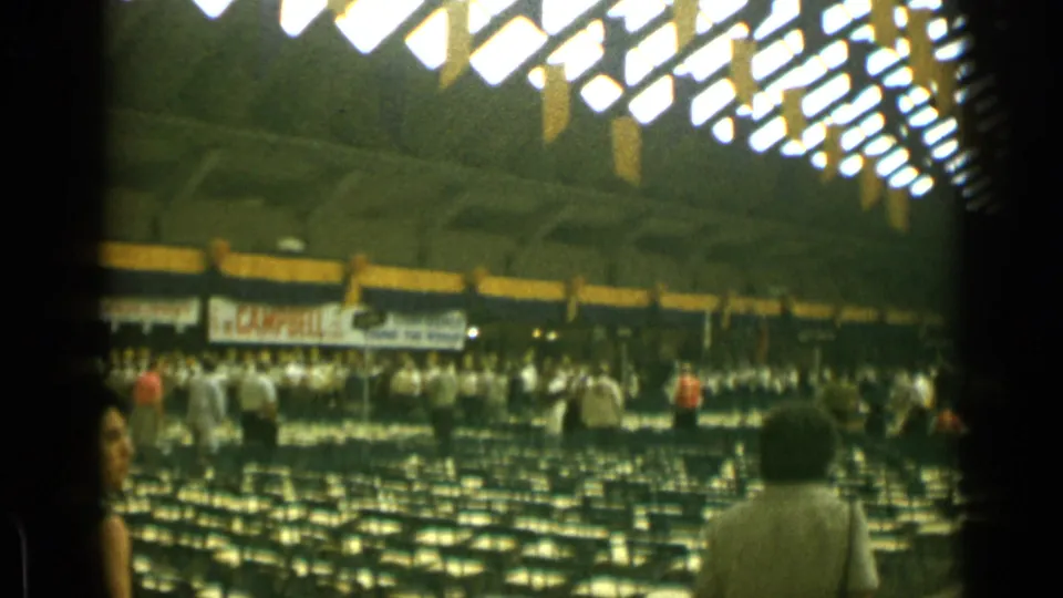 1962 Cannes auditorium view with rows of seating, attendees moving through aisles, overhead lighting, and partially readable venue signage.