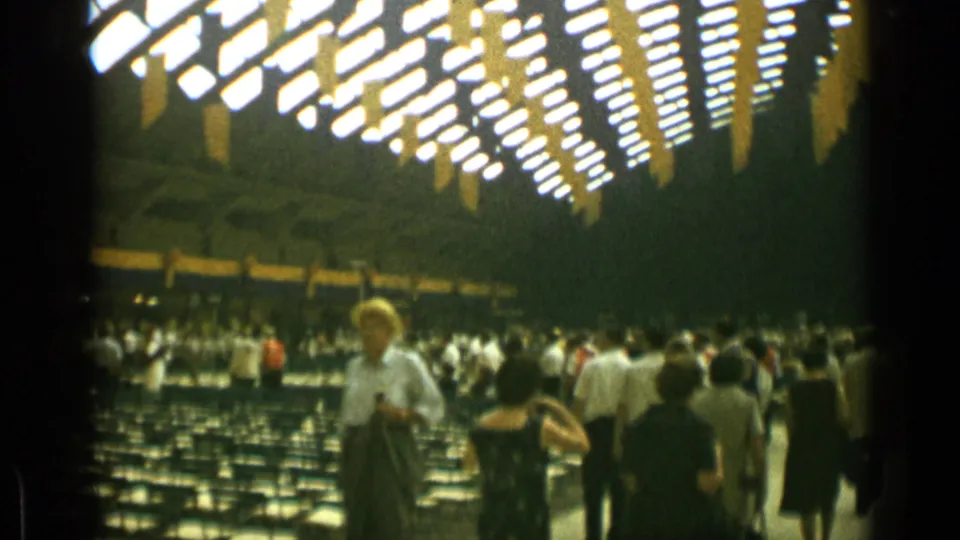 In the 1962 Cannes auditorium footage, a woman stands near the foreground while visitors move among chair rows behind her.
