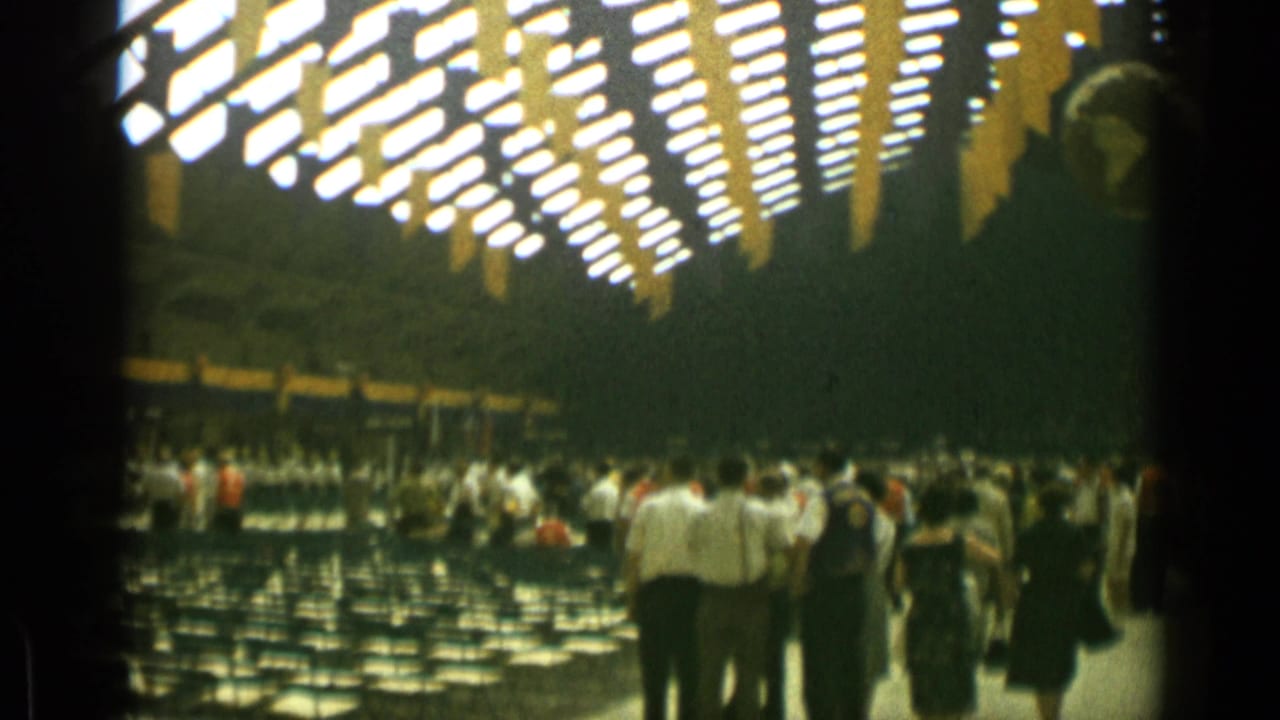 People walk through a hall with rows of chairs and a globe hanging in the background.