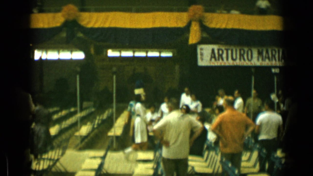Spectators face a small performance area with white-uniformed musicians and an Arturo Mariano banner.