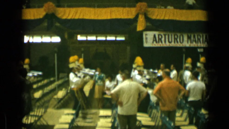 Cannes, France, 1962 frame showing spectators from behind as a uniformed band performs in a decorated indoor setting.