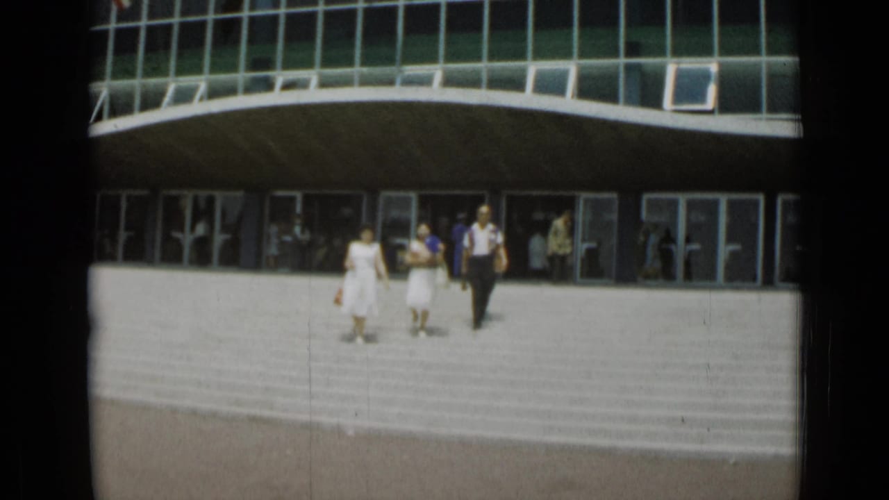 The group descends the broad exterior stairs in Cannes, with other visitors visible through and around the glass doors.
