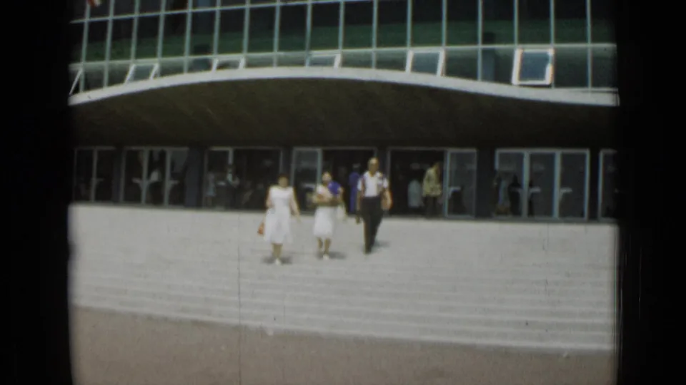 The group descends the broad exterior stairs in Cannes, with other visitors visible through and around the glass doors.