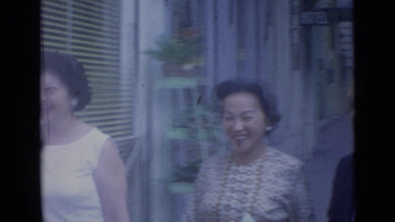 Two women walking past a shopfront, one smiling toward the camera.