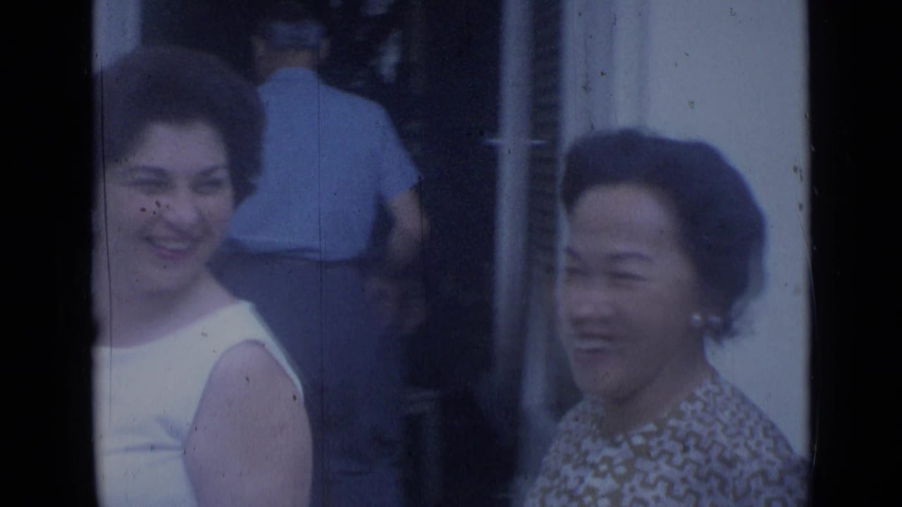 Two smiling women near a doorway, with a man seen from behind in the background.