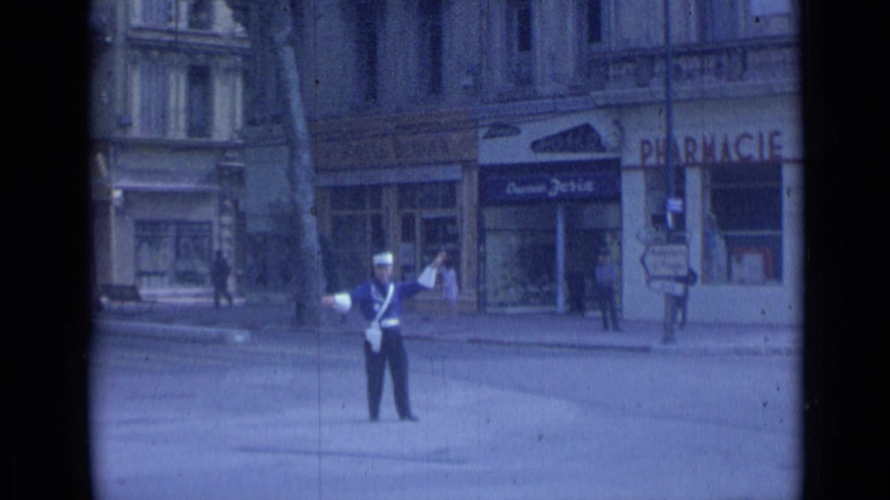 Traffic officer in a blue uniform directs street traffic near pharmacy and shopfront signs.