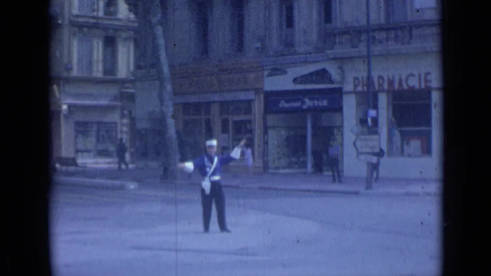 1962 Cannes street view with a uniformed traffic officer standing in the roadway before pharmacy and Cuisine Jolie storefronts.