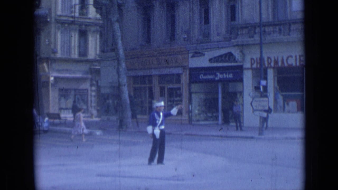 Traffic officer gestures with a baton as pedestrians and storefronts appear behind him.