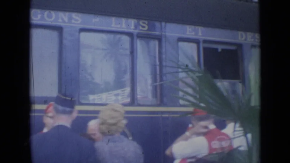 Close view of a blue passenger railcar in Cannes with platform crowds and partial route lettering visible above the windows.