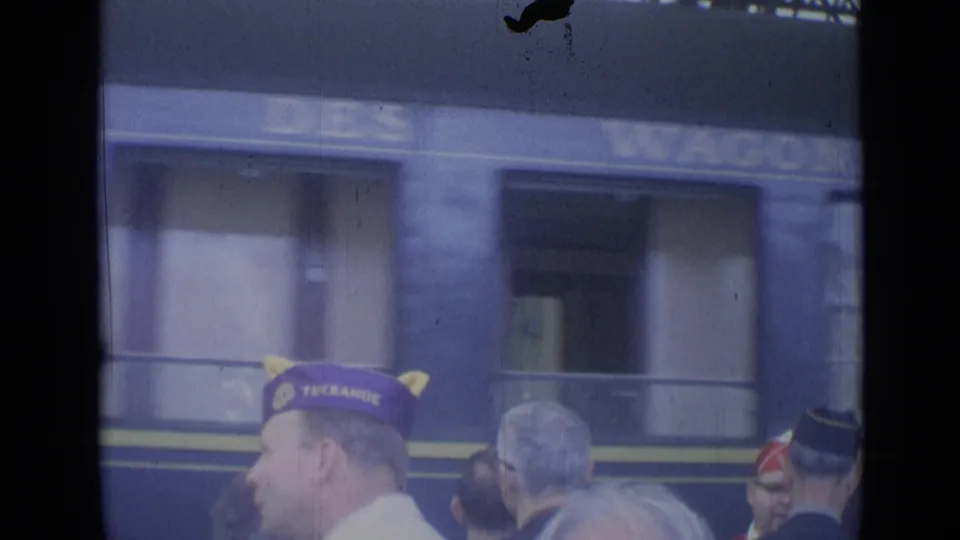 Cannes, France 1962 home-movie frame showing platform spectators in front of a passing blue rail carriage.