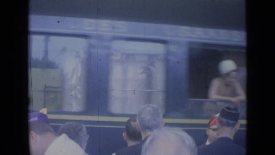 Cannes, France 1962 frame showing a passenger in a white hat at a train window while onlookers watch below.