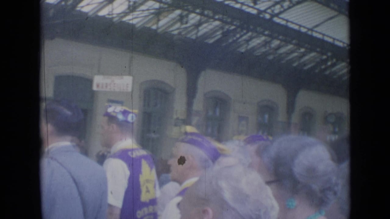 Crowd inside a train station near destination signage and arched windows.