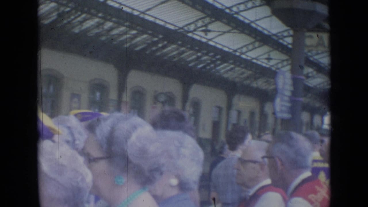 Crowded Cannes railway concourse in 1962, with travelers and group headwear visible under the arched roof.