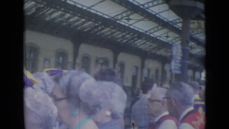Crowded Cannes railway concourse in 1962, with travelers and group headwear visible under the arched roof.
