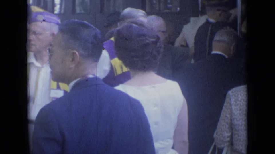 Cannes station passengers pass close to uniformed personnel, with formal clothing and hats visible in the 8mm frame.