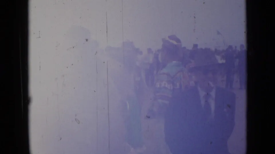 Faded 1962 Cannes home-movie frame with a uniformed or ceremonial figure partly visible before a crowd, softened by exposure damage.