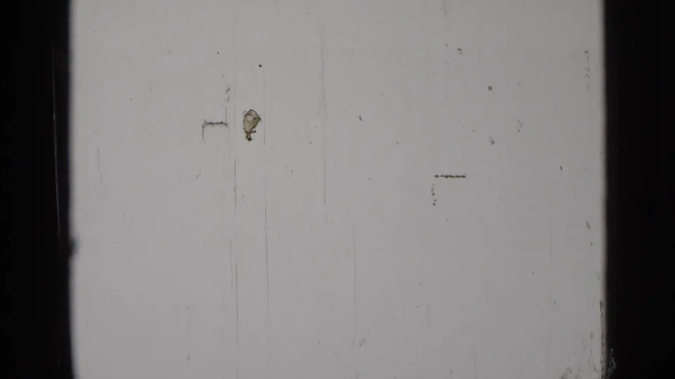 End frame from the 8mm clip showing mostly blank exposed film with scratches, dust, and edge marks rather than a clear subject.