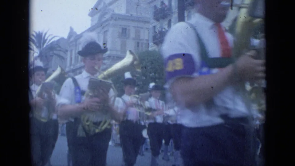 A close spectator view in Cannes shows a tuba player and other uniformed brass musicians moving through the parade.
