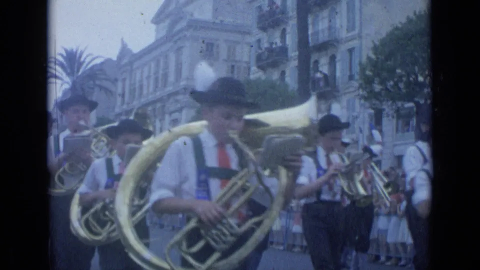 The final frame shows Cannes parade musicians clustered close to the camera, with large brass horns and spectators along the street.