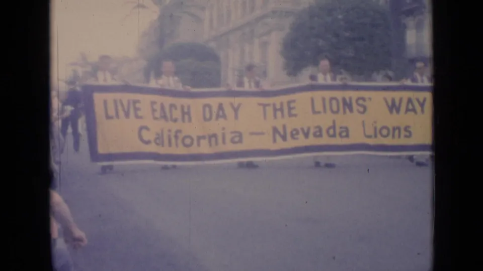 A California-Nevada Lions banner reading “Live Each Day the Lions’ Way” is carried down a Cannes street in 1962.