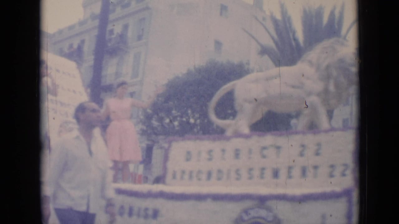 1962 Cannes parade float with a lion statue, a woman in a pink dress, and District 22 text visible on the side.