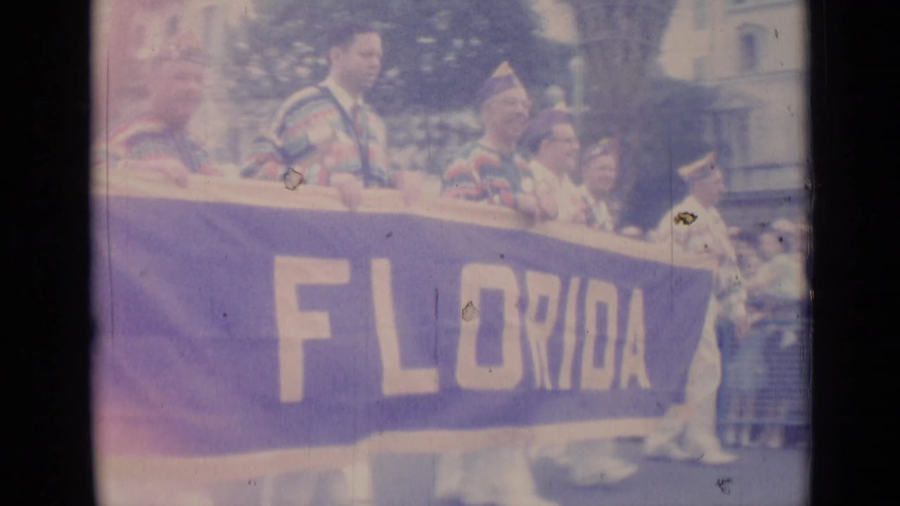 Costumed parade participants carry a large banner reading Florida.
