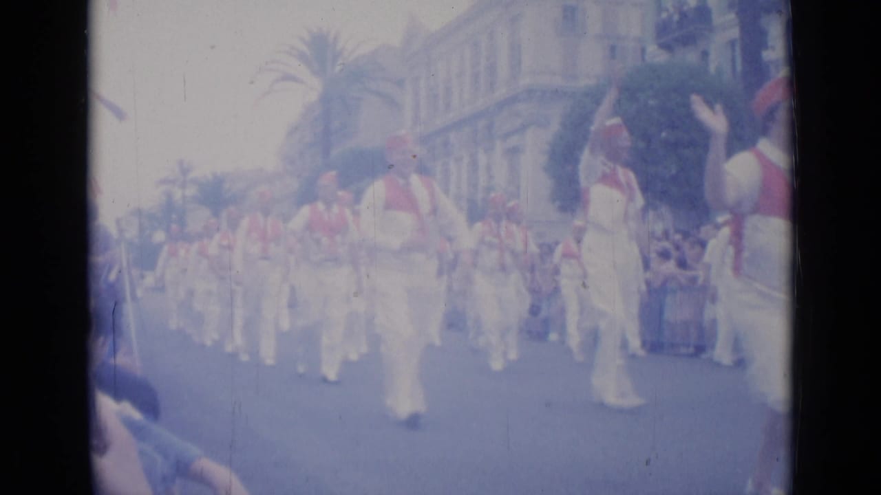 White-clad marchers move down a street past spectators.