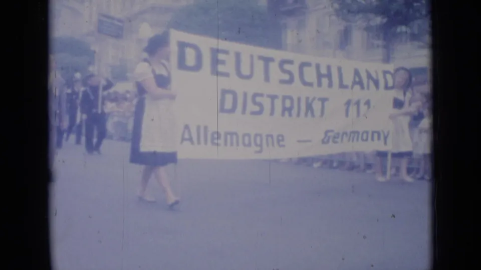A large parade banner reading Deutschland, Distrikt 111, Allemagne, Germany is carried along the Cannes street.