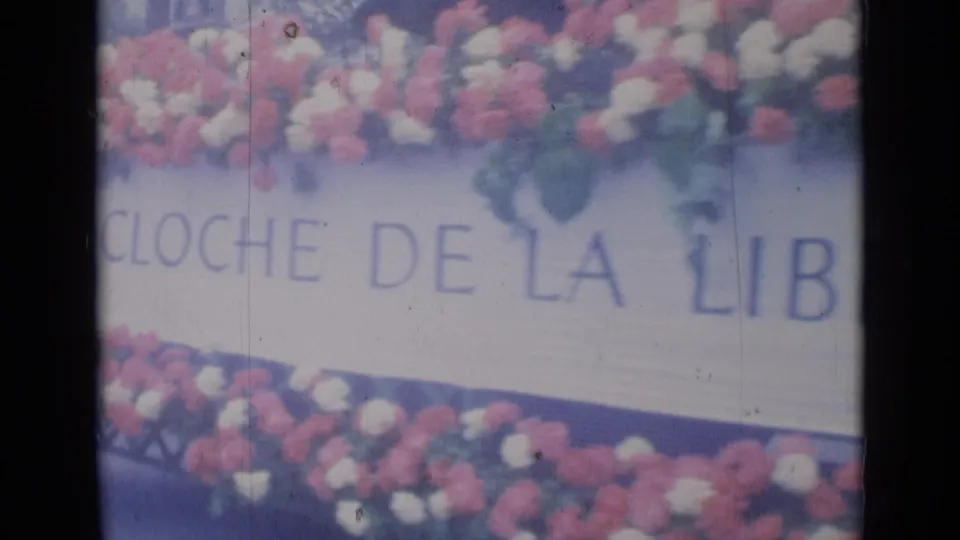 Close Cannes parade frame showing floral decorations and partial French text reading freedom bell on the float side.