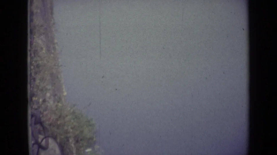A sparse 1962 Florence river view shows open water, a tree-lined edge, and soft color fading from the 8mm scan.